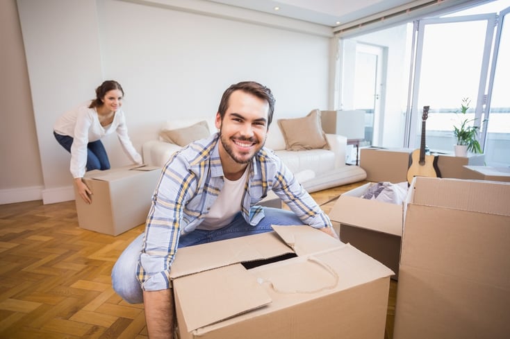 Cute couple unpacking cardboard boxes in their new home